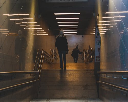 A modern commuter walking efficiently down the steps of an urban transit station platform