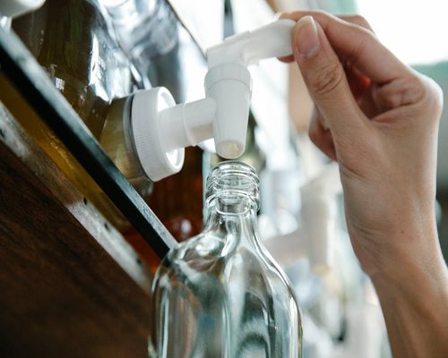 A person refilling a clean reusable water bottle at a modern workspace water dispenser