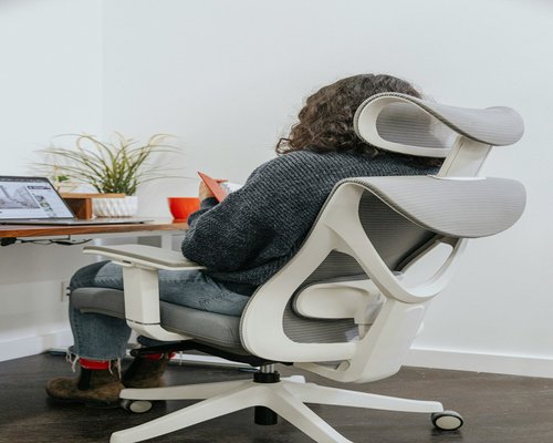 A simple full body stretching posture practiced next to a workspace chair